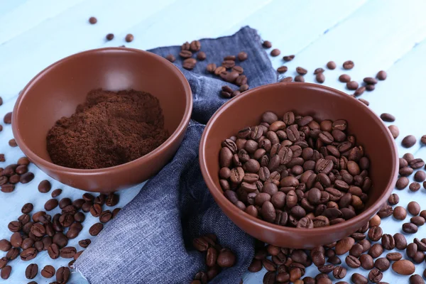 Dos tazones de café molido y granos de café sobre fondo de madera azul con material vaquero —  Fotos de Stock
