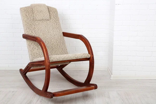 Cadeira de balanço confortável no chão de madeira perto do fundo da parede de tijolo — Fotografia de Stock