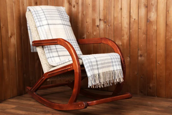 Кресло-качалка покрыто клетчатым фоном на деревянной стене — стоковое фото