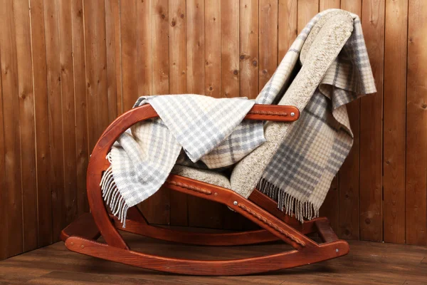 Rocking chair covered with plaid on wooden wall background — Stock Photo, Image