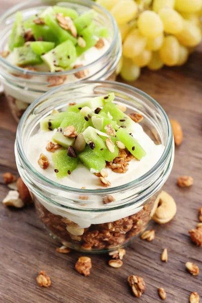 Gezonde gelaagde dessert met muesli en fruit op tafel — Stockfoto