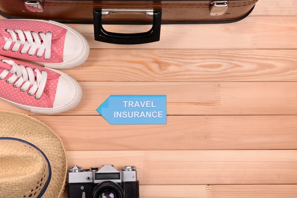 Koffer und Touristensachen mit Aufschrift Reiseversicherung auf hölzernem Hintergrund von oben — Stockfoto