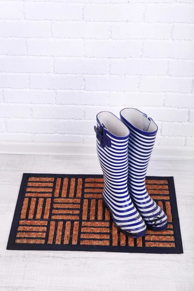 Stivali sporchi wellington sul tappetino della porta in camera — Foto Stock