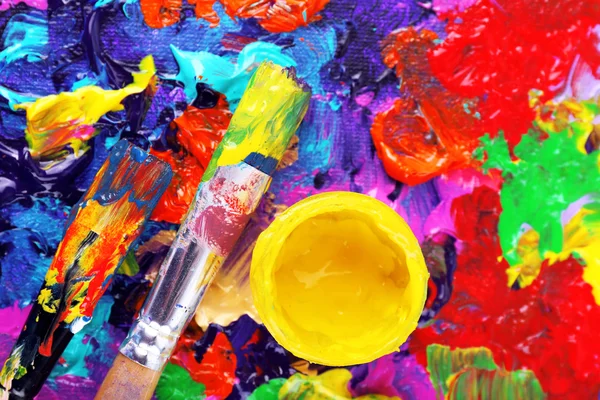 Cans of paint and brush on colorful painted background — Stock Photo, Image