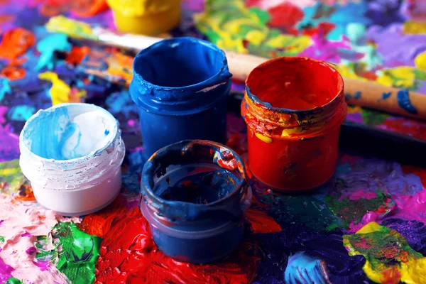 Банки фарби та пензля на барвистому пофарбованому фоні — стокове фото