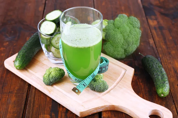 Glas grünen Smoothie mit Gemüse auf Schneidebrett auf Holztischhintergrund — Stockfoto