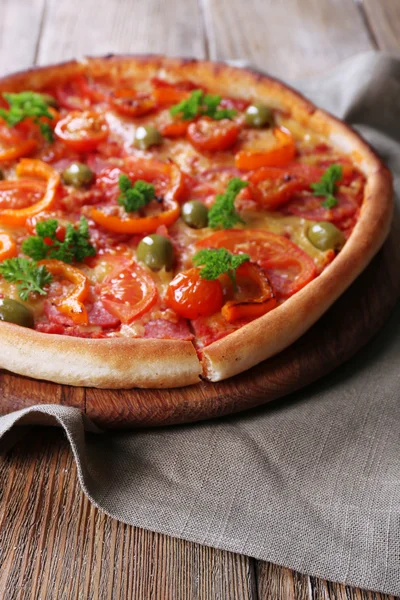 Ízletes pizza kolbásszal és zöldség zsákvászon ruhával és fából készült asztal háttere — Stock Fotó