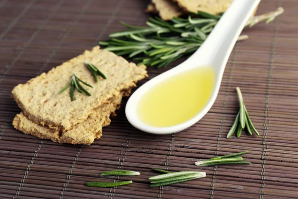 Crispbread com raminhos de alecrim e colher de óleo sobre fundo tapete de bambu — Fotografia de Stock