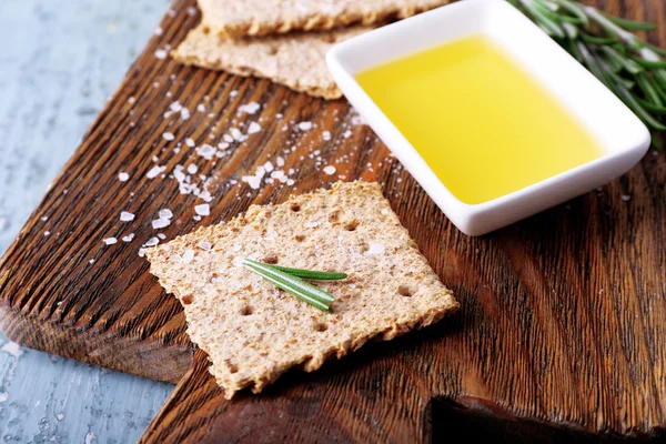 Crispbread with salt and of oil on cutting board, on color wooden table background — Stock Photo, Image