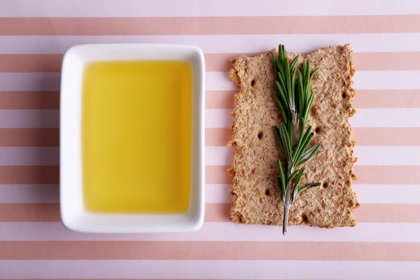 Crispbread com óleo e raminhos de alecrim sobre fundo listrado — Fotografia de Stock