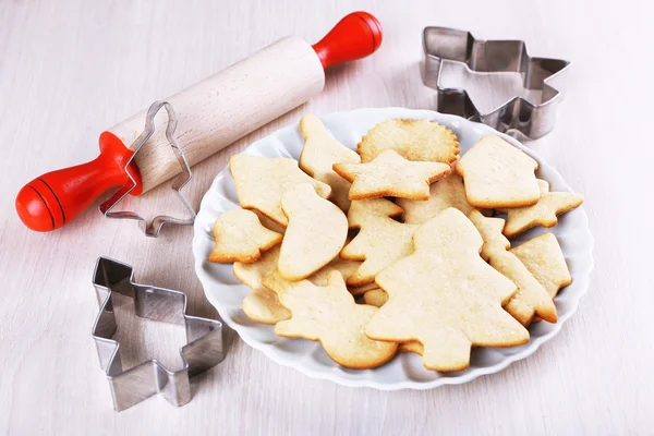 Gingerbread cookies on plate with copper cookie cutter and rolling pin on wooden table background — Stock Photo, Image