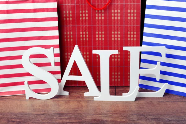 Sale with bags on wooden background — Stock Photo, Image