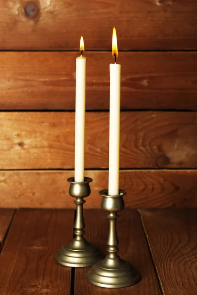 Retro candlesticks with candles on wooden background — Stock Photo, Image