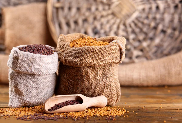 Mustard seeds in bags on  wooden background — Stock Photo, Image