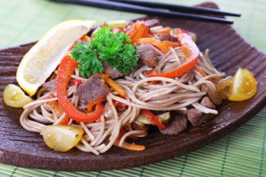 Bambu Hasır arka plan üzerinde plaka üzerinde kavrulmuş et ve sebze ile Çin eriştesi