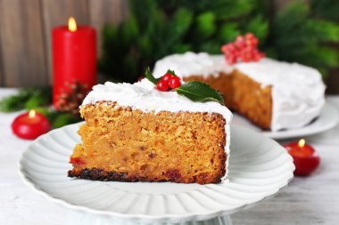 Pasta dilimi krem masada ahşap duvar arka plan üzerinde Noel dekorasyonu ile kaplı