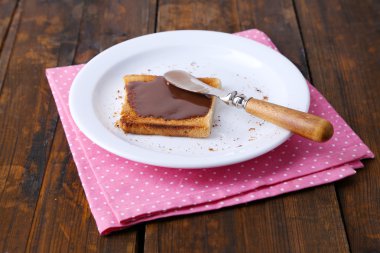 Çikolata plaka üzerinde bıçak ve peçete ahşap masa arka plan üzerinde yayılmış tost ekmeği