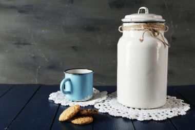 Süt olabilir ve dantel bardak altlığı peçete ahşap masa ve koyu arka plan üzerinde kurabiyeyle Kupası