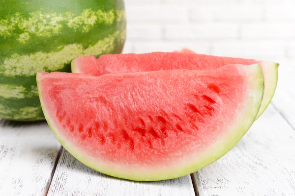 Juicy watermelon on table on brick wall background — Stock Photo, Image
