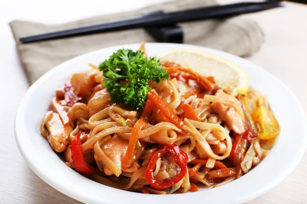 Fideos chinos con verduras y mariscos en plato sobre fondo de estera de bambú —  Fotos de Stock