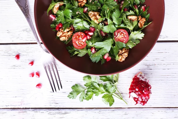 Fresh salad with greens, garnet and spices on plate on table close-up — Stock Photo, Image