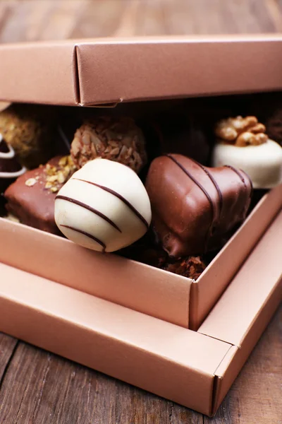 Caja llena de chocolates sobre fondo rústico de madera — Foto de Stock