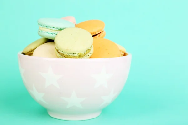 Assortment of gentle colorful macaroons in colorful bowl on color background — Stock Photo, Image