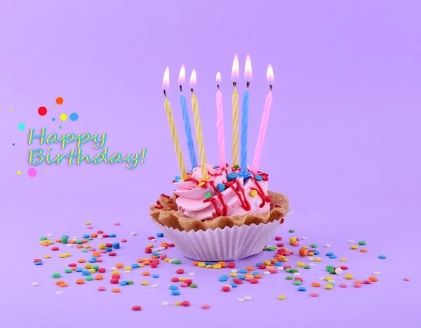 Bolo de xícara de aniversário com velas e brilhos coloridos no fundo roxo — Fotografia de Stock