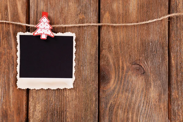 Blank photo frame and Christmas decor on rope, on wooden background — Stock Photo, Image