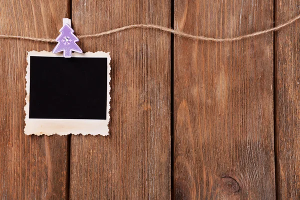 Marco de fotos en blanco y decoración de Navidad en cuerda sobre fondo de madera —  Fotos de Stock