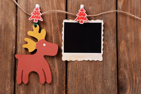 Marco de fotos en blanco y decoración de Navidad en cuerda, sobre fondo de madera —  Fotos de Stock