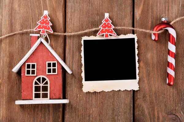 Moldura de foto em branco e decoração de Natal na corda, no fundo de madeira — Fotografia de Stock