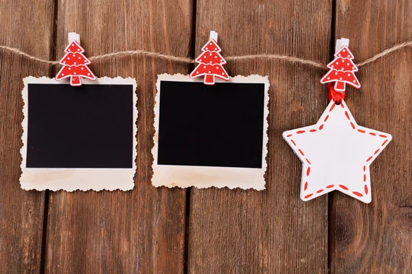 Blank photo frames and Christmas decor on rope, on wooden background — Stock Photo, Image