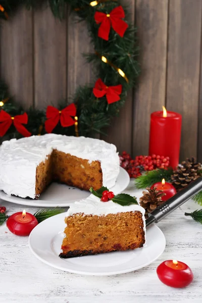 Rebanada de crema cubierta de pastel con decoración de Navidad en la mesa, sobre fondo de pared de madera — Foto de Stock