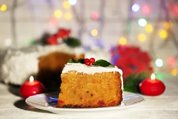 Fetta di crema ricoperta di torta con decorazione natalizia sul tavolo, su sfondo luminoso — Foto Stock