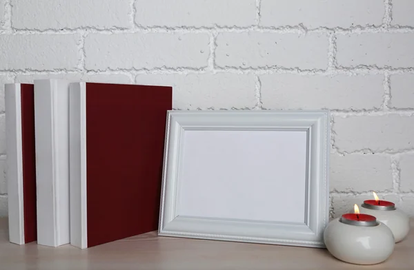 Marcos de fotos con velas y libros sobre superficie de madera, sobre fondo de pared de ladrillo —  Fotos de Stock