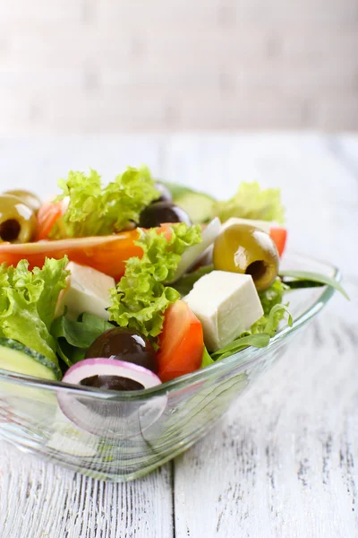 Greek salad in glass dish on color wooden table background — Stock Photo, Image