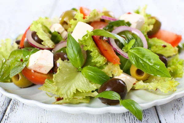 Greek salad in plate on color wooden table background — Stock Photo, Image