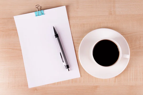 Kopje koffie op schotel met vel papier en pen op houten tafel achtergrond — Stockfoto