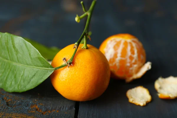 Sappige rijpe mandarijnen met bladeren op houten tafel — Stockfoto