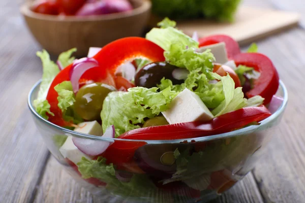 Griekse salade in glas schotel op houten tafel achtergrond — Stockfoto