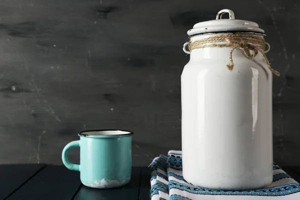 Mjölk kan och cup på träbord och mörk bakgrund — Stockfoto