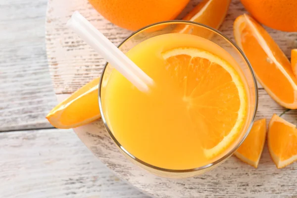 Vaso de zumo de naranja con paja y rodajas sobre fondo de mesa de madera —  Fotos de Stock