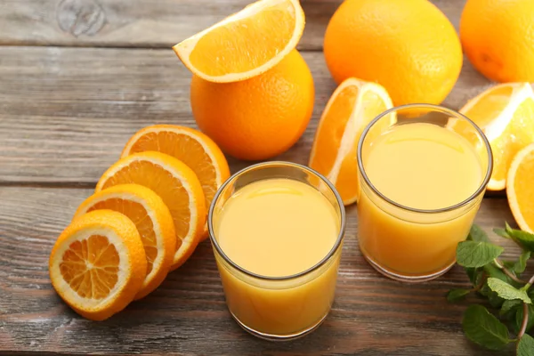 Bardak portakal suyu ve ahşap masa arka plan dilimleri — Stok fotoğraf