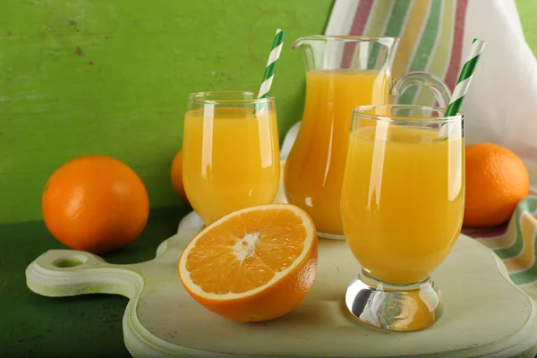 Kieliszek soku pomarańczowego z plastrami i paski tkaniny na zielonym tle — Zdjęcie stockowe