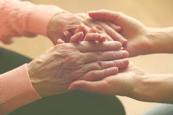 Old and young holding hands on light background, closeup — Stock Photo, Image