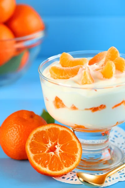 Gustoso dessert al latte con mandarino fresco in ciotola di vetro, su sfondo di legno a colori — Foto Stock