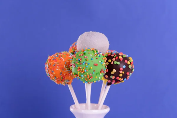 Sweet cake pops in vase on blue background — Stock Photo, Image