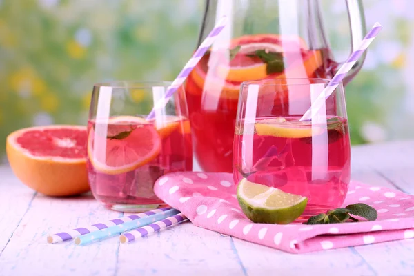 Limonada rosa en vasos y jarra sobre mesa sobre fondo natural —  Fotos de Stock