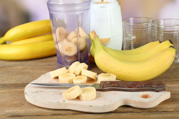 Banana fatiada na tábua de corte, na mesa de madeira, no fundo brilhante — Fotografia de Stock